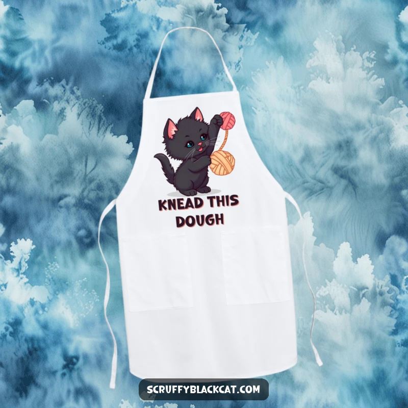 Funny kitten apron showing a scruffy black kitten batting at a dangling yarn ball, adding humor to cooking.
