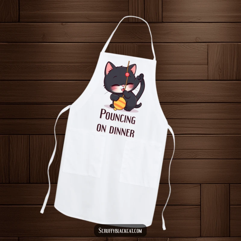 Funny apron depicting a small black cat playfully batting at a dangling string toy, perfect for kitchen tasks with feline fun.