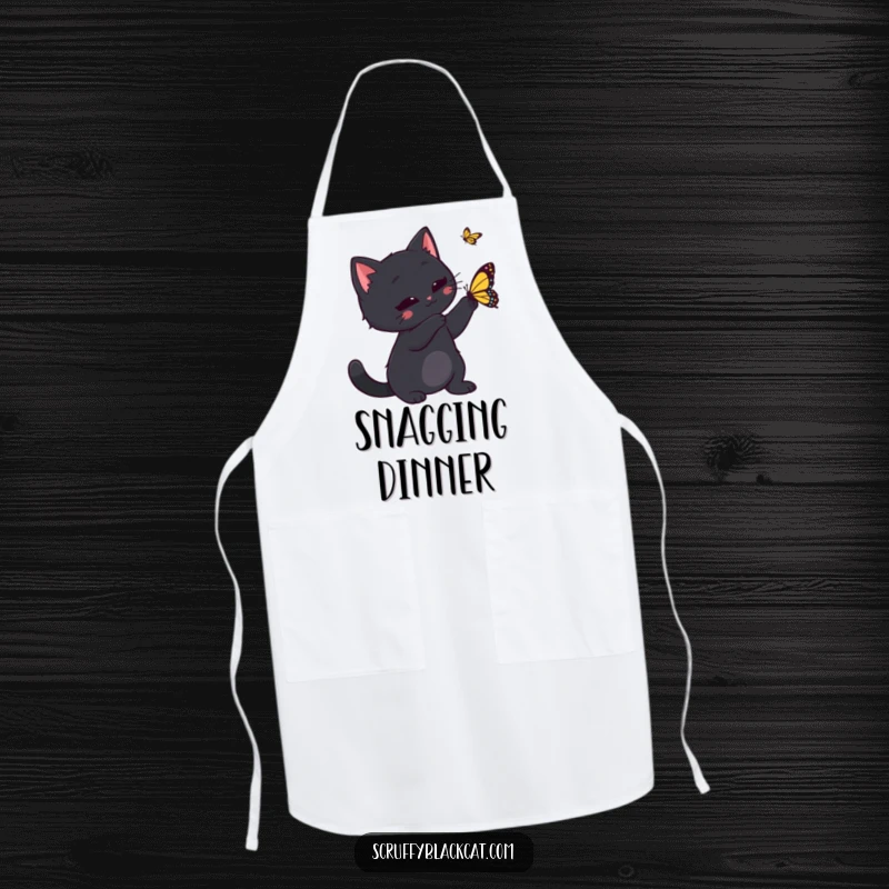 Funny black cat playfully swatting a butterfly while cooking, illustrated on a practical apron for humorous kitchen adventures.