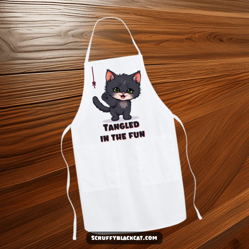 Funny apron depicting a scruffy black kitten batting playfully at a dangling string, ready for kitchen fun.