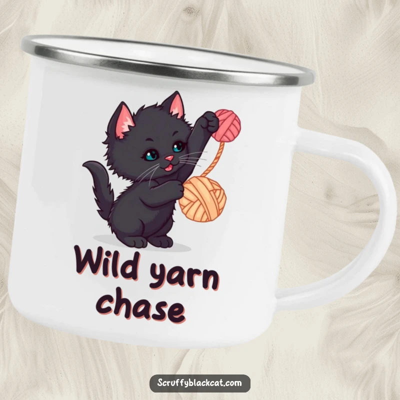 Funny kitten camping mug with a scruffy black kitten batting at a dangling yarn ball, perfect for outdoor fun and smiles.