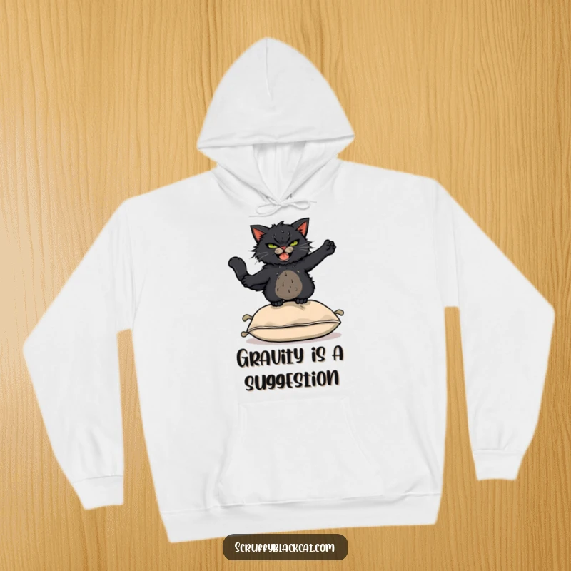 Funny Hoodie: Scruffy black cat with a mischievous grin leaping acrobatically over a cushion, showing off athletic silliness.