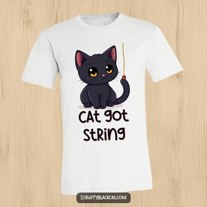 Funny black cat t-shirt showing a sleek cat with big, round eyes energetically batting at a dangling string, embodying playful curiosity.